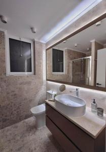 Un baño con lavabo, inodoro y espejo. en Mini City Escape, en Rodas