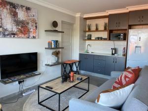 a living room with a couch and a tv and a table at Tulip On The Bay in Mossel Bay