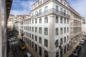 a tall white building on a city street with a tram at Pombalino Design Apartment em BaixaChiado in Lisbon