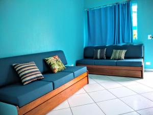 Chalés Céu e Mar Ubatuba في أوباتوبا: كنبتين زرقاوين في غرفة معيشة بجدران زرقاء