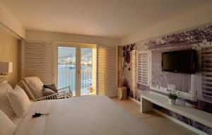 a bedroom with a large white bed and a television at Hotel Osejava in Makarska