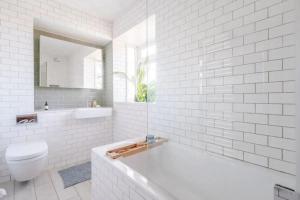 a white bathroom with a tub and a toilet at Peaceful 2 Bedroom Flat with Roof Terrace - Hackney in London