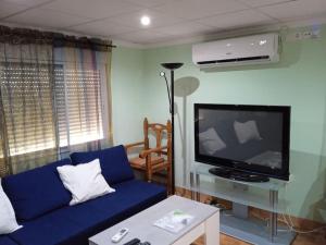 sala de estar con sofá azul y TV de pantalla plana en Planta superior independiente con piscina - barbacoa, 