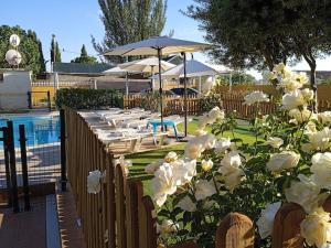 a fence with white flowers next to a pool at Planta superior independiente con piscina - barbacoa 
