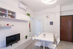 a white dining room with a white table and a tv at Appartamento Bilocale TA in Follonica