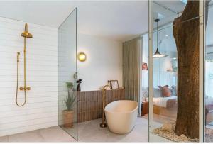 a bathroom with a bath tub and a bedroom at wyn in Ko Larn