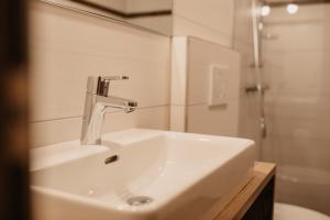 Appartement Steinerhof في فيرفينفينغ: وجود مغسلة بيضاء في الحمام مع دش