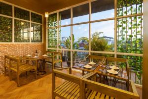 een restaurant met tafels en stoelen en grote ramen bij Nina Angkor Residence in Siem Reap