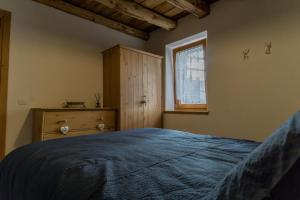 um quarto com uma cama azul e uma janela em Casa Claudia - Casa Vacanze em Domegge di Cadore