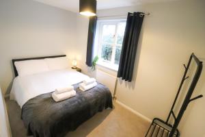 a bedroom with a bed and two towels on a bench at Chic 2BR Flat in Bishop's Stortford in Bishops Stortford