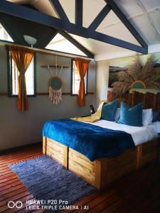 a bedroom with a large bed with a blue blanket at Treur River Lodge in Moremela