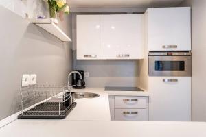 Una pequeña cocina con gabinetes blancos y un fregadero. en Sun Studio, en Valbonne 2 fotos más