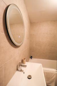 a bathroom with a sink and a mirror and a tub at Chic 2BR Flat in Bishop's Stortford in Bishops Stortford