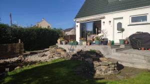 a house with a stone retaining wall in front of a yard at Chilowen - Happy House in Inverkeithing