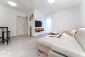 a white living room with a white couch and a table at Villa Hlapa-new modern villa near beach - by TRAVELER tourist agency Krk in Gostinjac