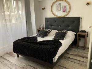Schlafzimmer mit einem großen Bett mit einem schwarzen Kopfteil in der Unterkunft ATH hôtel Athénée in Cannes