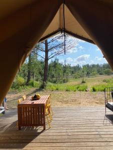 卡爾康的住宿－Camping la Kahute, tente lodge au coeur de la forêt，木制甲板配有木桌和椅子