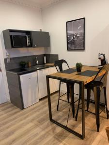 uma cozinha com uma mesa e uma cozinha com um micro-ondas em La Clé des Plaisirs em Chambéry