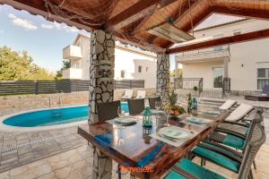 a patio with a table and chairs and a swimming pool at Villa Hlapa-new modern villa near beach - by TRAVELER tourist agency Krk in Gostinjac