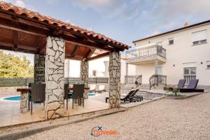 a patio with chairs and a table and a building at Villa Hlapa-new modern villa near beach - by TRAVELER tourist agency Krk in Gostinjac