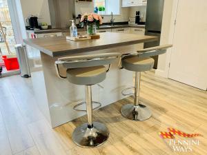 a kitchen with a island with two bar stools at Bleabeck View, Middleton-In-Teesdale in Middleton in Teesdale