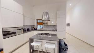 a kitchen with white cabinets and a counter with stools at Spacious 3 bedroom maisonette in Sliema