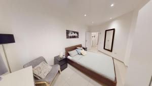 a white room with a bed and a chair at Spacious 3 bedroom maisonette in Sliema