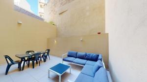 a patio with a blue couch and a table and chairs at Spacious 3 bedroom maisonette in Sliema
