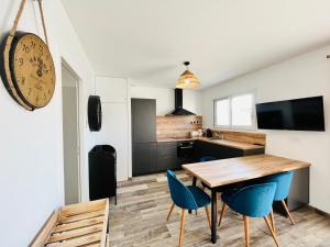 une cuisine et une salle à manger avec une table en bois et des chaises bleues dans l'établissement Maison forestière, mer & lumière, à Saint-Jean-de-Monts