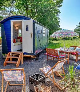 a blue trailer with chairs and a table and an umbrella at Finest Retreats - Shrawardine Train Carriage in Shrawardine