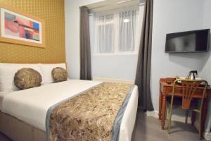sypialnia z łóżkiem, biurkiem i telewizorem w obiekcie Pembridge Palace Hotel w Londynie