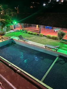 a swimming pool at night with two chairs in it at Pousada Melodia in Nova Friburgo