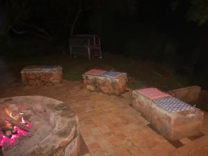 a brick patio with a fire pit and a grill at Treur River Lodge in Moremela