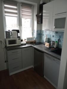 a kitchen with white cabinets and a sink and a microwave at Słoneczne studio in Szczawnica