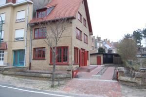 a brick house with red doors on a street at Villa Mowgli in De Panne