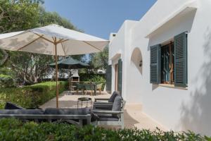 un patio con sillas, una sombrilla y una mesa en Villa Dora en Cala d´Or