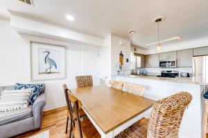 格爾夫海岸的住宿－A Wave From It All - Unit B，厨房以及带木桌和椅子的客厅。