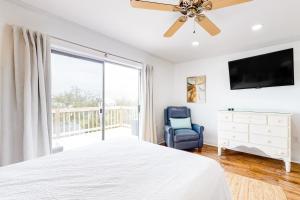 1 dormitorio con 1 cama, TV y silla en A Wave From It All - Unit B, en Gulf Shores