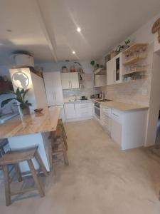 a kitchen with white cabinets and a table and chairs at Private modern cottage in St Francis with big secure garden in St Francis Bay