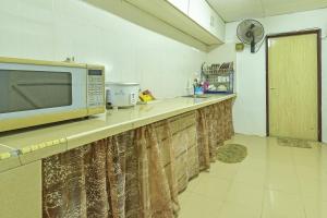 OYO HOME 90692 Tok Babah Village Homestay في Kampong Sungai Mati: وجود ميكروويف للجلوس على منضدة في المطبخ