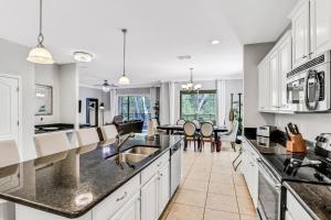 a kitchen with white cabinets and black counter tops at Paradise Palms Esate - Paradise Palms Resort in Kissimmee