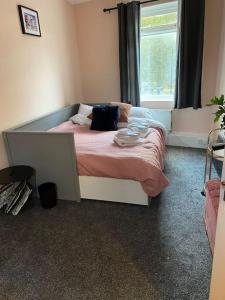 um quarto com uma cama com lençóis cor-de-rosa e uma janela em 2 Bedroom flat on Tottenham High Rd. em Londres
