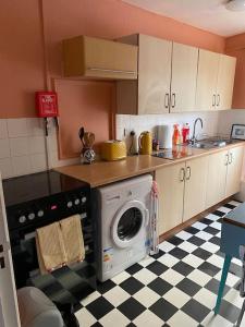 uma cozinha com uma máquina de lavar roupa e um piso em xadrez em 2 Bedroom flat on Tottenham High Rd. em Londres