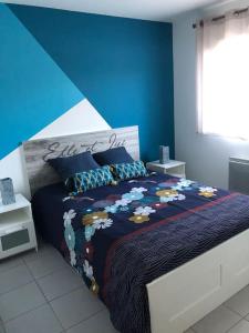 een slaapkamer met een bed met een blauwe muur bij Maison chaleureuse lac & mer in Hourtin