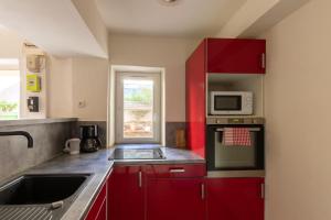 a kitchen with red cabinets and a microwave at Le Beaumier in Cuges-les-Pins