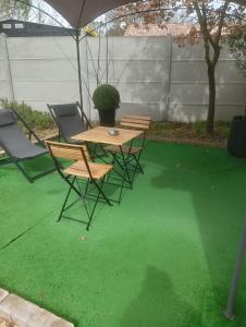 a patio with a table and chairs on a green floor at La Chouette Villa ,chambre de 20m2 totalement indépendante avec terrasse in Cannes-et-Clairan