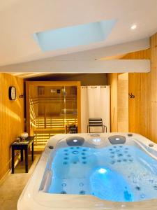 eine große Badewanne in einem Zimmer mit einem Zimmer in der Unterkunft LA CLEF DES CHAMPS 61 in La Chapelle-Souëf