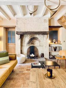 - un salon avec une grande cheminée en pierre dans l'établissement LA CLEF DES CHAMPS 61, à La Chapelle-Souëf