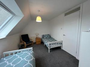 a bedroom with a bed and a chair and a window at Walk to Everything in Crail - Land Sea Cottage in Crail
