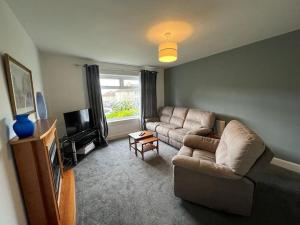 a living room with a couch and a tv at Walk to Everything in Crail - Land Sea Cottage in Crail